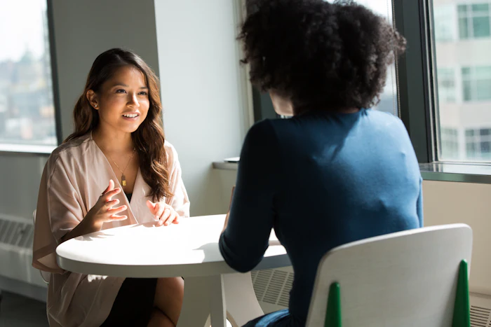 Duas mulheres conversando sentadas a uma mesa